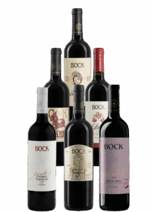 Group of seven Bock wine bottles arranged together, showcasing white and red labels with gold accents.